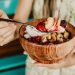 Healthy acai smoothie bowl with fresh berries and nuts held in a wooden bowl.